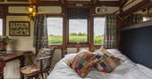 Sofa bed with colourful pillows, looking out the windows out to the rolling downs of Dorset at Camping Coach