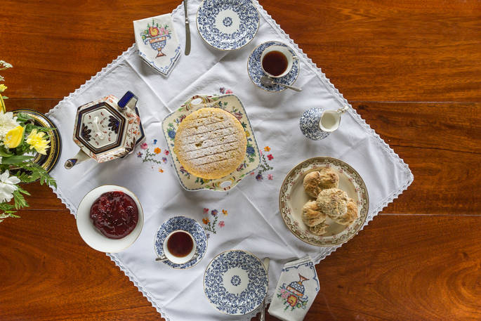 Delicious cream tea and Victoria Sponge cake on beautiful decorated antique plates and hand-stitched table cloth and serviettes at Camping Coach, Dorset