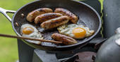 Breakfast of sausages and eggs being cooked on the pan at Laverstock's Everdene Hut, Dorset