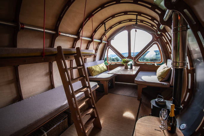 The Fuselage set up as a living room space with seating next to the window with views of the Cotswolds