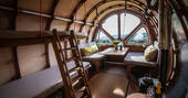 The Fuselage set up as a living room space with seating next to the window with views of the Cotswolds