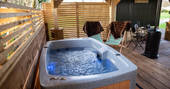 Hot tub on the decking next to Willow the shepherd's hut at The Wright Retreat in Gloucestershire