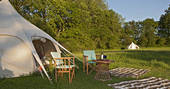 Sit outside your bell tent in the evening sun with a glass of wine at Wild Wood Bluebell in Gloucestershire