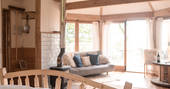 Look across the large living space with comfy sofa, log burner and table to sit at, at Venn Treehouse in Herefordshire