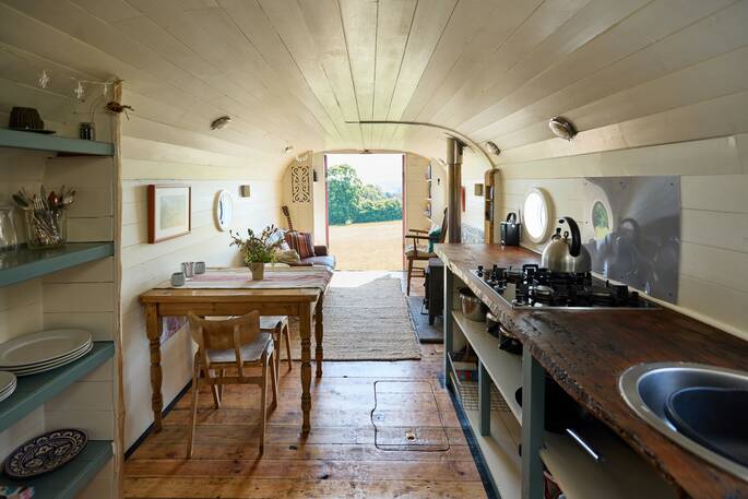 Kitchen equipped with gas hobs, cooking utensils, crockery, glassware and dining table for two