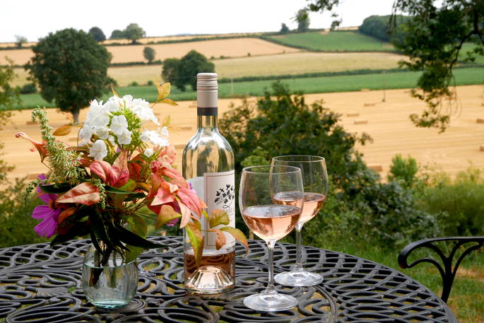 A bottle of rosé and two glasses on the table outside Myrtle shepherd's hut, with amazing views of the Herefordshire countryside