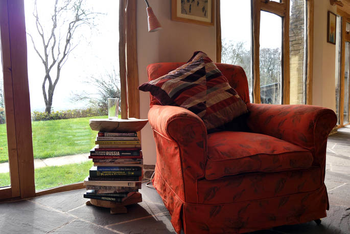 A handcrafted bookcase side table sits next to an armchair in The DugOut's open plan living space