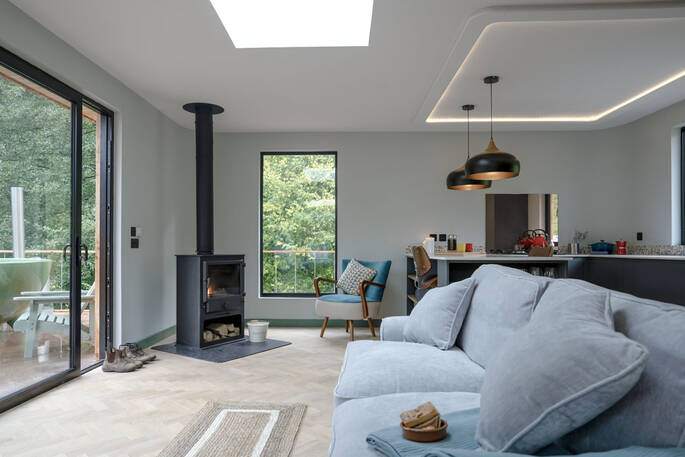 Open plan kitchen and lounge with a sofa and wood burner