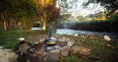 Millie the Hut shepherd's hut cooking by the river, Wegnalls Mill, Presteigne, Herefordshire - Owen Howells Photography