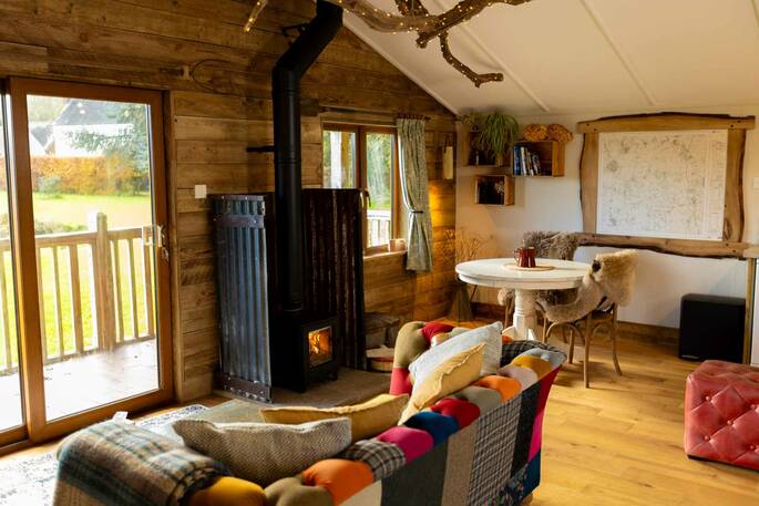 Open plan living area with sofa, and wood burner