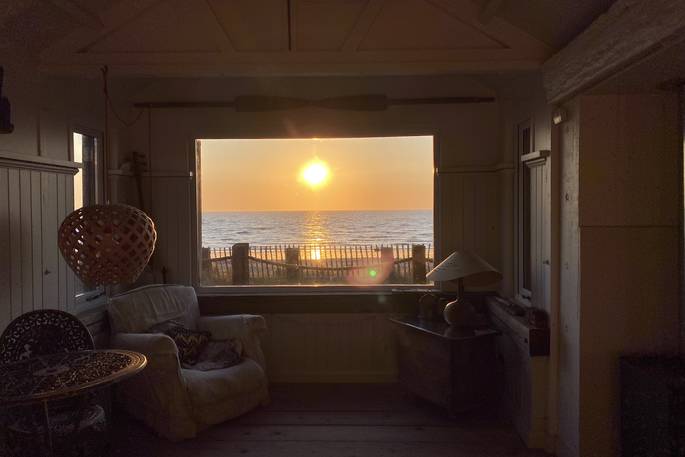 The Beach House cabin interior view of the sea and sunset, Isle of Sheppey, Kent, England
