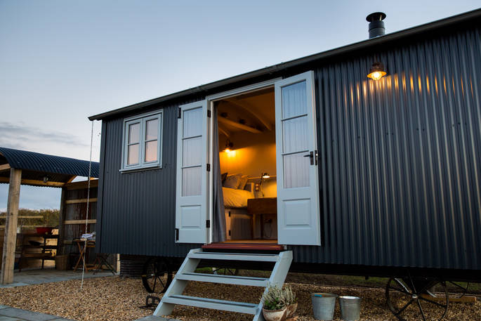Austin, the shepherd’s hut, with the front doors open in the evening at Tin and Wood