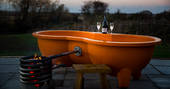 Relax in the outdoor hot tub with a glass of bubbly outside your shepherd’s hut at Tin and Wood
