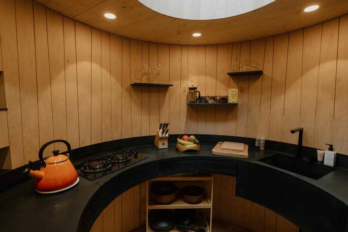 Curved kitchen with cooking utensils, hob, kettle and fridge