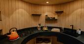 Curved kitchen with cooking utensils, hob, kettle and fridge