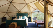 A view of the spacious bedroom space with natural light flooding in at the Oyster Catcher geodome in Norfolk