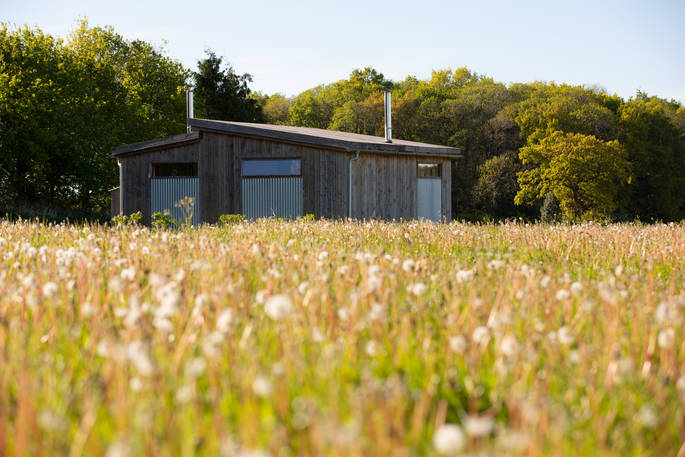 A view of Woodcock Cabin across the wild flower meadow at Bagthorpe Farm in Norfolk