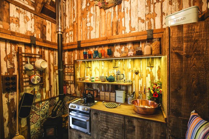 Beautifully crafted cabin interior made from reclaimed timber with well-equipped kitchen and woodburner