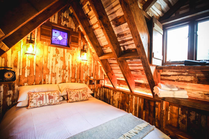 King-size mezzanine bedroom with reclaimed timber cladding up in the rafters of Rowan cabin in Northumberland