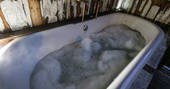 Outdoor bath full of bubbles for a indulgent wild wash at Rowan cabin in Northumberland