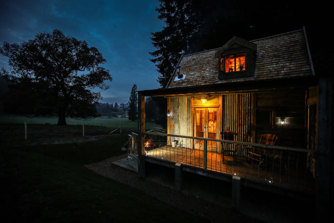 Rowan cabin exterior at night. The outdoor deck is the perfect spot to stargaze at night with the fire pit going and sat in a rocking chair