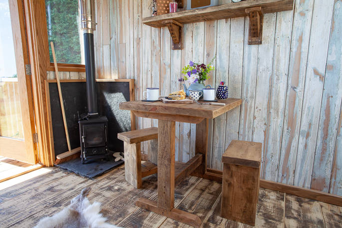 Sit by the wood-burner inside Cheviot at Huts in the Hills in Northumberland 