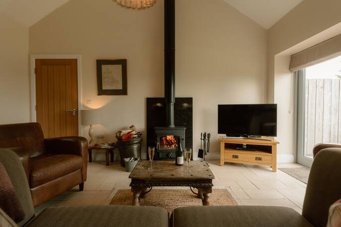 Open plan living area with tv, wood burner and sofa