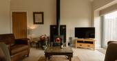 Open plan living area with tv, wood burner and sofa