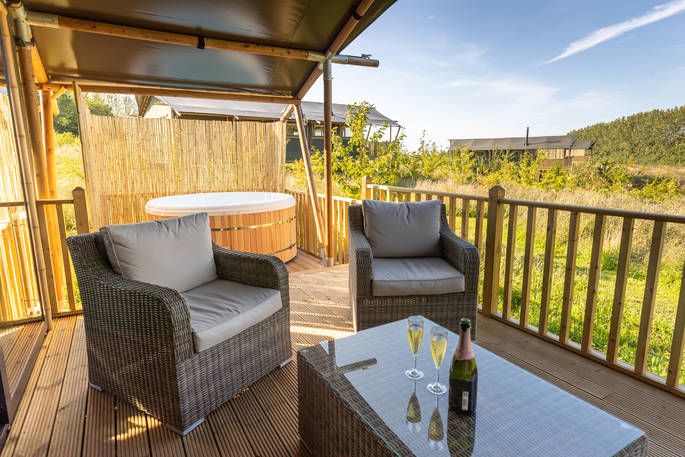 Pop open the prosecco and enjoy a chilled glass sat outside on the decking of your safari lodge at Bird Holme Glamping in Nottinghamshire
