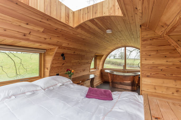Relax in the comfortable double bed at Cheriton Treehouse in Somerset