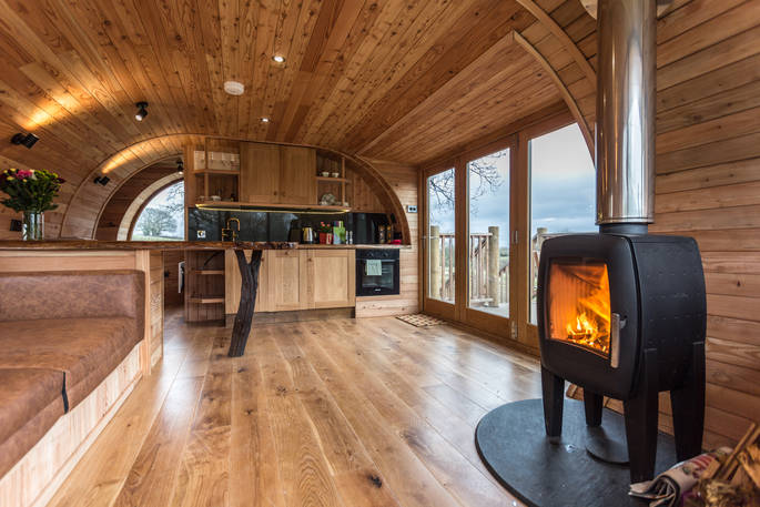 Handcrafted interior space of Cheriton Treehouse with roaring woodburner, built-in kitchen and french doors out onto elevated terrace