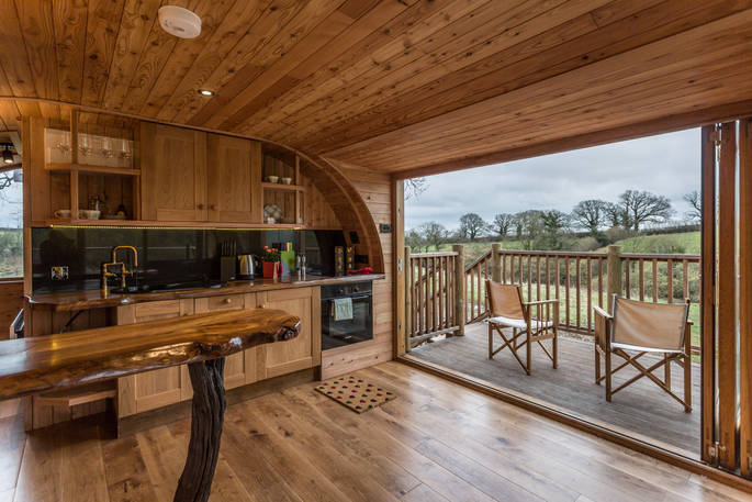 Waney wood breakfast bar and fully equipped kitchen with french doors leading out to balcony with view out across the pond
