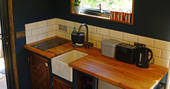 Kitchenette with two induction hobs, sink, kettle, toaster and cooking utensils and crockery