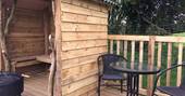 Wooden shed with barbecue, and garden table and chairs standing on wooden decking