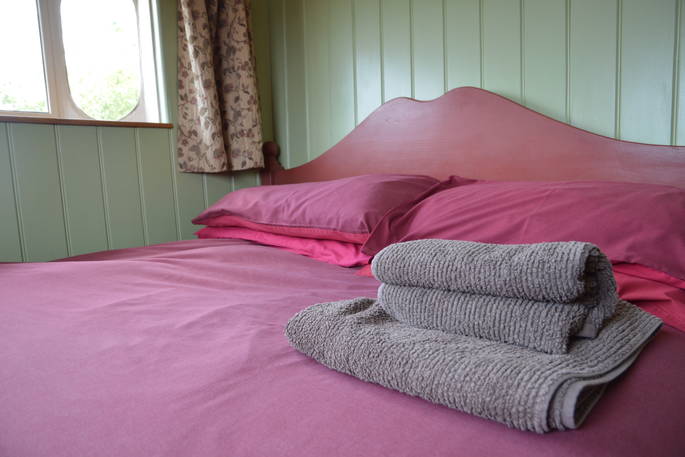 Main bedroom with double bed inside Maroon Fairground Wagon at Coppins Farm in Suffolk