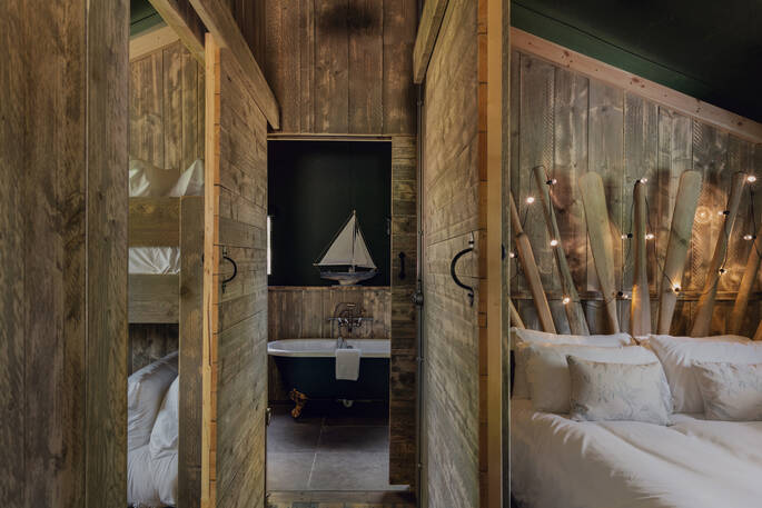 King-size bed and roll top bath tub inside The Fisherman's Hideaway at The Lost Garden Retreat in Suffolk