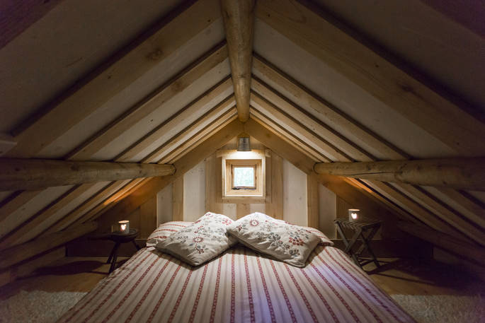 Cosy double bed on mezzanine level accessed by ladder inside Idaho Cabin at Forest Garden