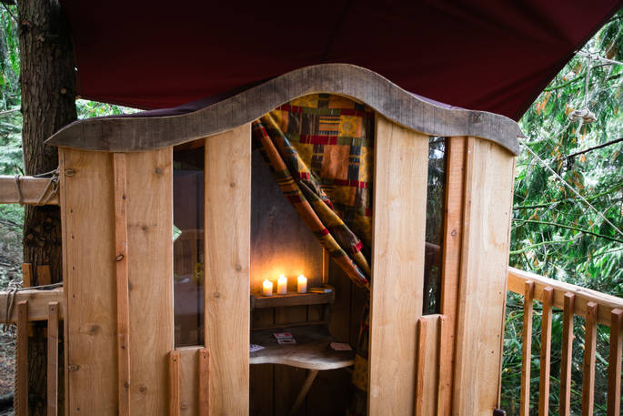 Sit in the 'confessional' that is heated by candles and play card games on the folded down table at Puckshipton Treehouse  