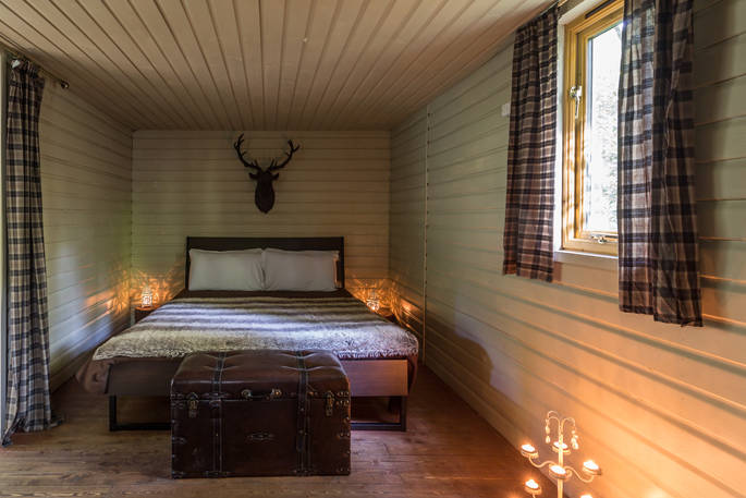 The bedroom area inside Deer Wood cabin at Jollydays, with comfortable kingsize bed and fluffy throw