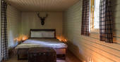 The bedroom area inside Deer Wood cabin at Jollydays, with comfortable kingsize bed and fluffy throw