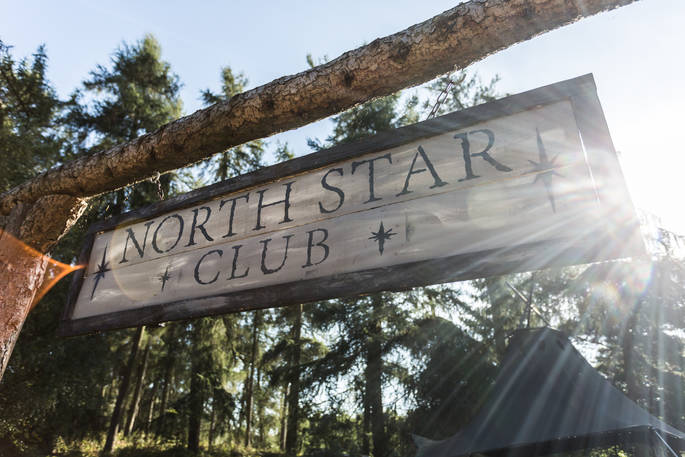 Sun filtering through the trees onto the North Star Club sign