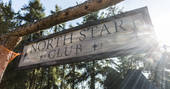 North Star Club wooden sign with sun filtering through the trees
