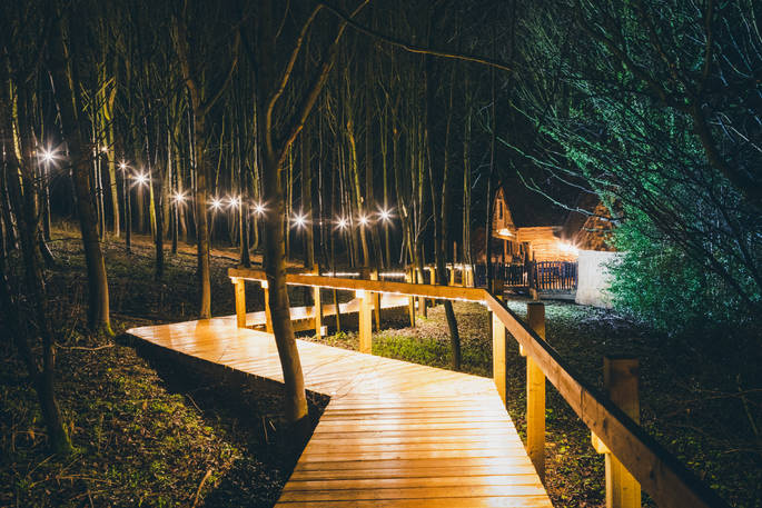 Wooden path leading to Rufus's Roost that's lit up in the night sky at The Hideaway in Yorkshire