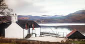 The Douglas Boathouse cabin exterior with view to the lake Loch Fyne, fields and hills, Argyll & Bute, Scotland