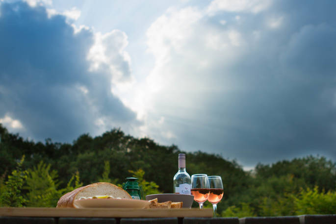 Delicious fresh bread and rosé wine laid on the picnic table outside Gwdihw shepherd's hut at Ty Cerrig