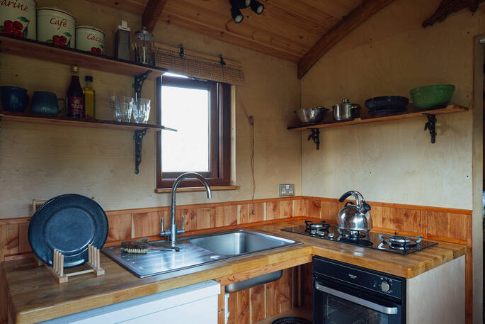 Kitchen equopped with a two-ring gas hob, oven, undercounter fridge and cooking utensils