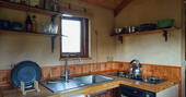 Kitchen equopped with a two-ring gas hob, oven, undercounter fridge and cooking utensils