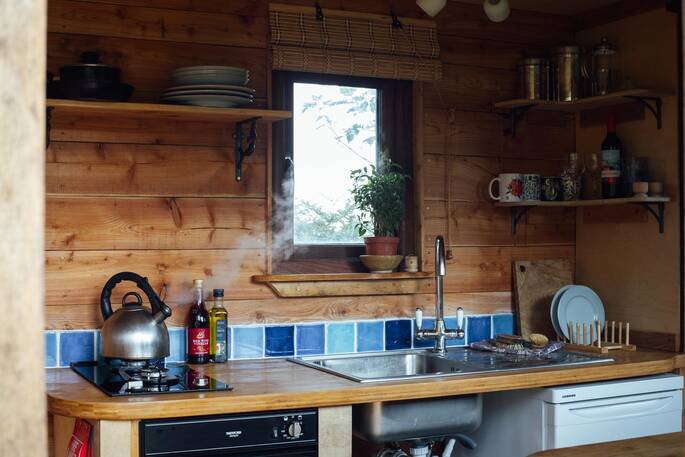 Kitchen equipped with a two-ring gas hob, kettle, oven and cooking utensils