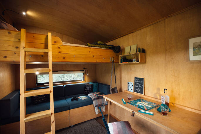 Open plan layout cabin with kitchenette, seating area and bed on the mezzanine