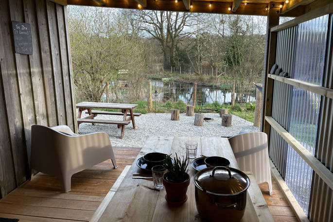 The Den cabin - view to the lake from the outdoor covered kitchen dining area, One Cat Farm, Lampeter, Ceredigion, Wales